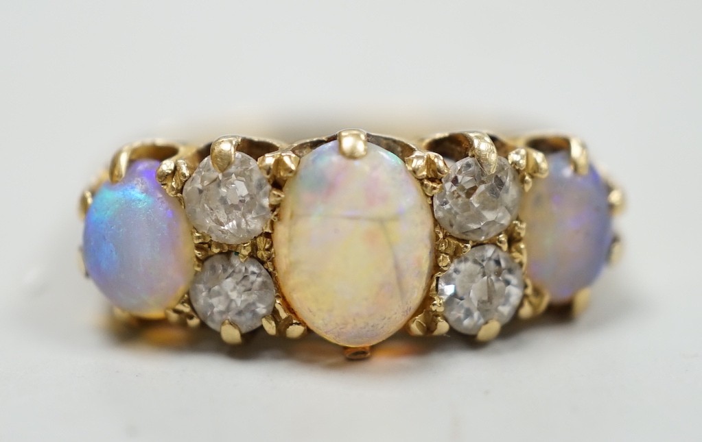 A late Victorian 18ct gold, three stone white opal and four stone diamond set half hoop ring, size M, gross weight 4.2 grams.
